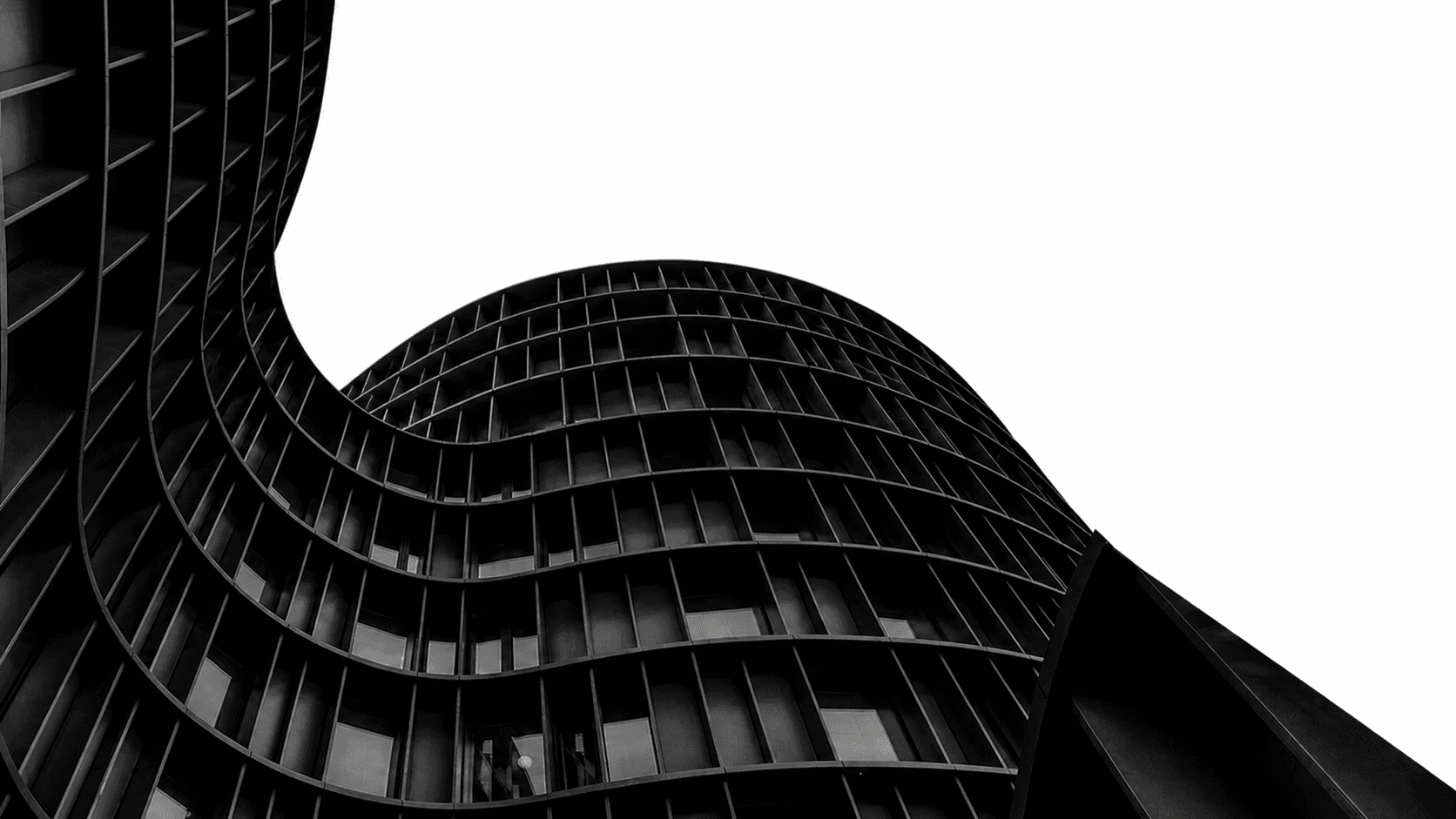 A curved black high-rise building against an open sky